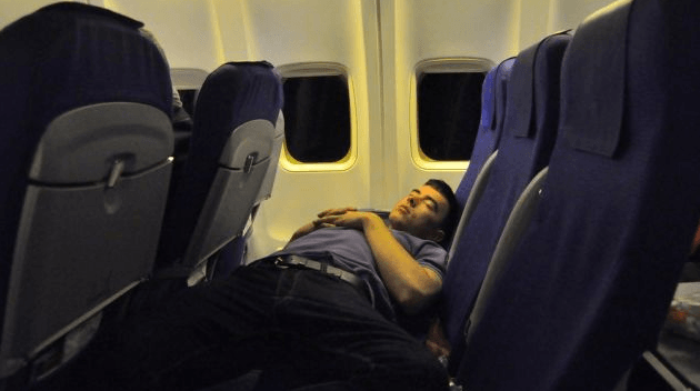 man asleep across airplane seats