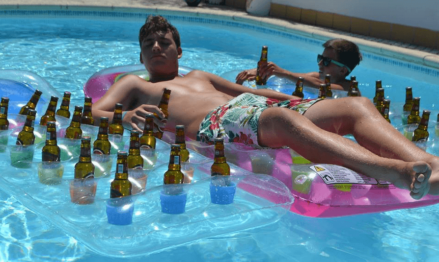 man relaxing in a pool with a beer