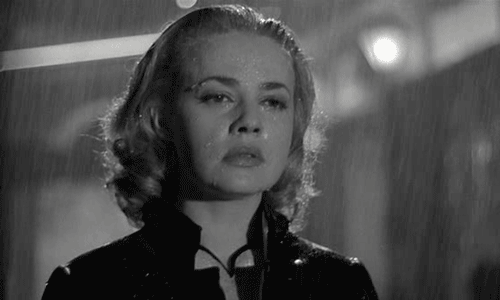 Gif. Black and white close up of a woman walking in the rain