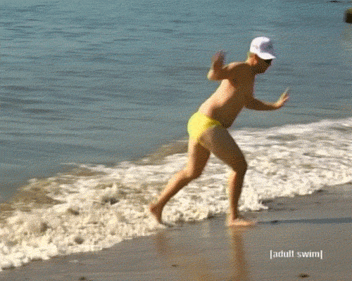 Man running away from water on beach GIF