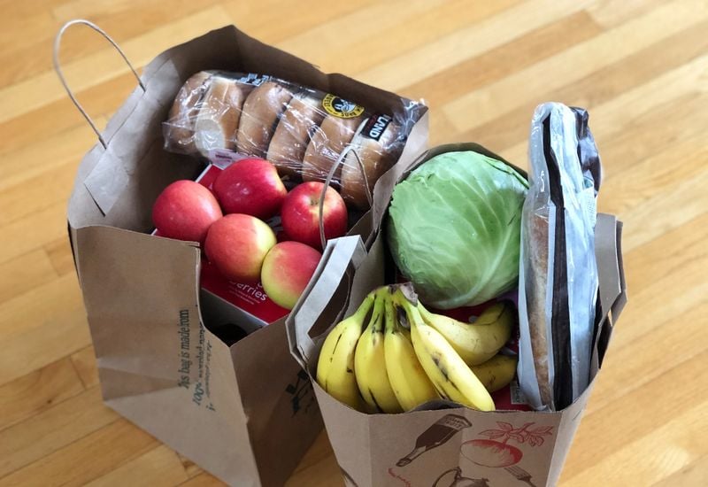 Two paper bags with groceries, including fresh fruit and a packet of bagels